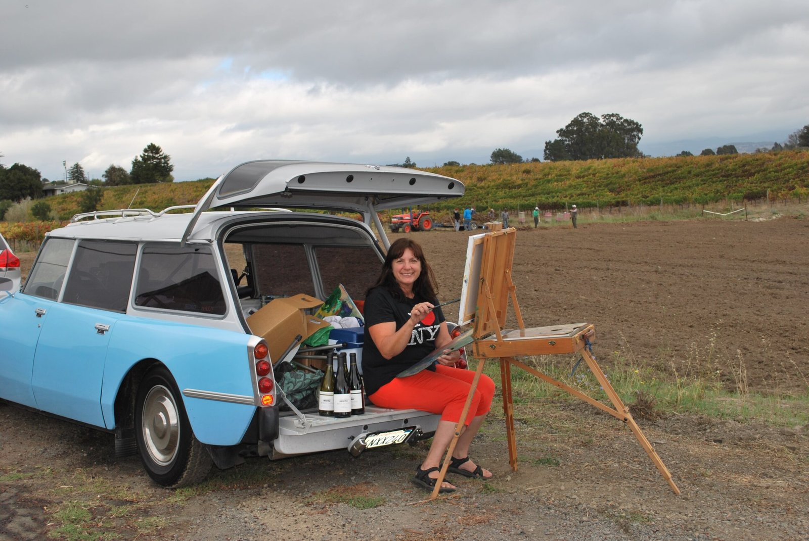 Susan Kendall painting on location with her blue 1972 Citroën DS 21 wagon as outdoor studio