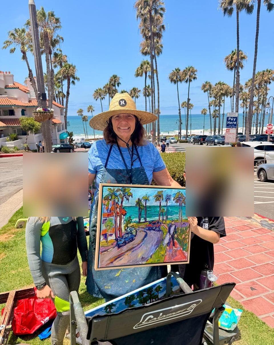 Susan Kendall holding a sold Calafia Beach painting in San Clemente; children in the photo are blurred for privacy.